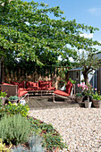 Terrace with red lounge furniture and potted plants in the summer garden