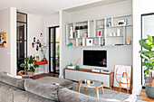Bright living room with open shelving wall, discreet decoration and house plants