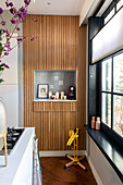 Modern wall niche with wooden slats and decorative elements next to the window in the kitchen