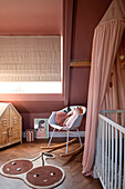 Kinderzimmer mit rosa Wandfarbe, Schaukelstuhl und Kirsch-Teppich