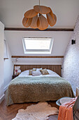 Bedroom with sloping ceiling, natural light and hanging lamp