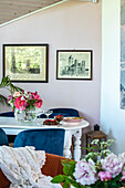 Essbereich mit blauen Samtstühlen und Blumenstrauß auf weißem Tisch