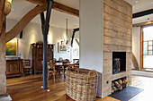 Fireplace as room divider in converted barn, dining area in the background
