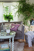 Wohnzimmer mit Pflanzen und grauem Sofa