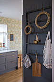 Wall with hooks for kitchen utensils and decorative wreaths in country-style kitchen