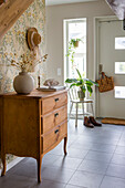 Hallway with vintage chest of drawers and floral wallpaper