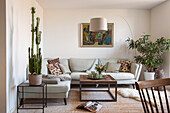 Living room in light colors with sofa, houseplants, painting and arc lamp