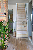 Eingangsbereich mit Holztreppe, Ziegelwand und Topfpflanze