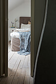 Blick ins Schlafzimmer mit Polsterbett und gehäkelter hellblauer Decke