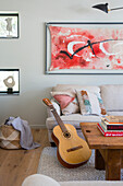 Wohnzimmer mit Akustikgitarre, Sofa und abstraktem Gemälde