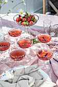 Gedeckter Gartentisch mit Erdbeeren und sommerlichen Getränken