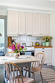 Kücheneinrichtung im Landhausstil mit Holztisch und buntem Blumenstrauß