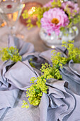 Festlich gedeckter Tisch mit Serviette und gelbgrünen Blüten