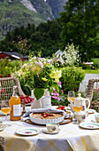 Gedeckter Tisch im Freien mit Blumenstrauß und Bergpanorama im Hintergrund