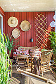 Terrace with rattan furniture and red wooden wall
