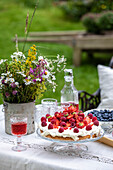 Sommerliches Picknick mit Beerentorte und Wildblumenstrauß im Garten