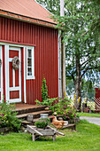 Ländliches rotes Holzhaus mit Gartendekoration und Hühnern