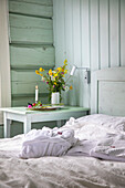 Farbenfroher Blumenstrauß auf weißem Beistelltisch neben dem Bett