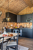 Holzvertäfelte Küche mit schwarzen Schränken und modernen Hängelampen
