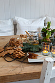 Gitter mit Lebkuchen-Bäumchen, Kerzen und winterlicher Dekoration auf einem Tisch