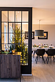 Festively laid dining table, Christmas tree and modern pendant light