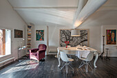 Bright dining room with dark wooden floor, white walls and artwork