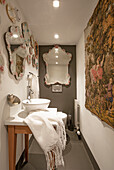 Narrow bathroom with kitsch mirrors and tapestry