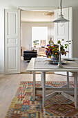 Dining table with flowers, colourful carpet, open doors
