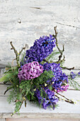 Hyacinth (Hyacinthus) in shades of purple and pink arranged with twigs to create a winter arrangement