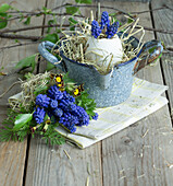 Egg shell filled with grape hyacinths (Muscari) in an enamel pot and bouquet with primrose and grape hyacinths, Easter decoration