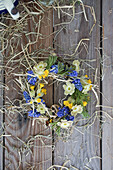 Wreath of grape hyacinths (Muscari), primroses (Primula veris), primroses and hay
