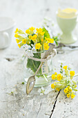 Bouquet of spring flowers in jar with silver spoon as place setting