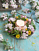Kranz aus Apfelblüten und Löwenzahn in Backform, mit Kerze