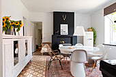 Dining room with round table, different chairs and sunflowers on white sideboard