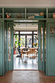 View through sliding door into dining room with large windows, wooden furniture and plants