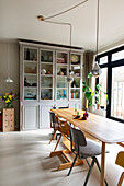 Wooden table with different chairs in front of a large display cabinet in the dining room