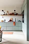 Modern kitchen in green with open shelves and black wall lamps