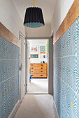 Hallway with geometric patterned wallpaper and pendant light