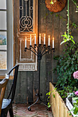 Candlestick with burning candles in front of wood panelling in the garden shed