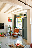 Reading chair and floor lamp in light-colored living room with plants