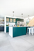 Modern kitchen with green-blue kitchen island and white bar stools