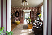 Living room with patterned wallpaper, leather sofa and antique wooden furniture