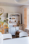 Living room with vintage wooden cupboard, decorations and rattan rocking chair