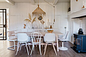 Country-style dining room with rattan hanging lamp and white-painted wooden walls