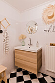 Modern bathroom with black and white chequerboard floor and wooden furniture