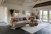 Bright living room with corner sofa, rattan tables and wooden beamed ceiling