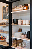 Black display cabinet with crockery and storage containers in a kitchen