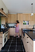 Modern kitchen with light-coloured wooden cabinets and black stone worktop