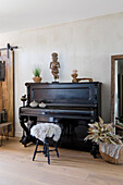 Black piano with stool and ethnic sculptures
