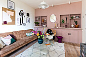 Living room with antique pink walls, built-in shelves and brown leather sofa
